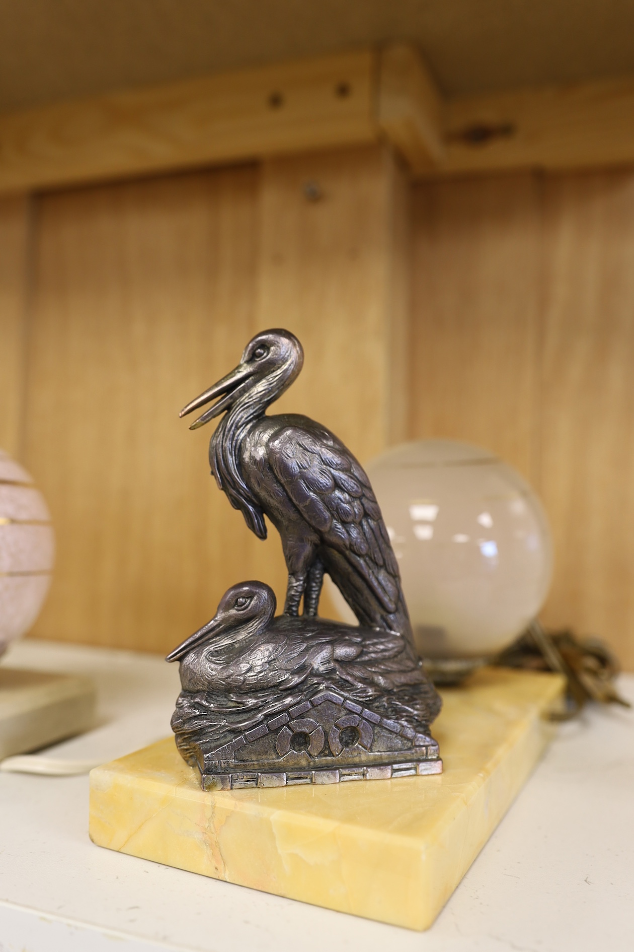 Two Art Deco lamps, one with a model of a dog the other of two pelicans, both with circular glass shades, largest 20cm wide. Condition - fair